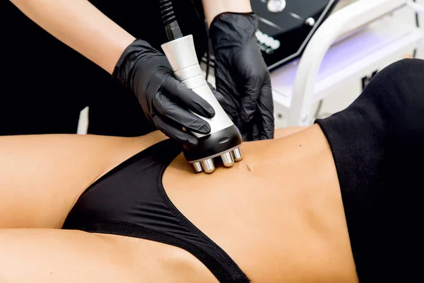 The doctor performs radiofrequency lifting on a woman to lose weight. Cosmetology office for figure correction. Cosmetic hardware procedures and massage for weight loss. Beautiful slender woman undergoing the procedure