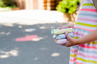 Çizim için renkli tebeşir tutan çocuğun yakın çekim. Açık hava eğlencesi. kaldırım çizimi 