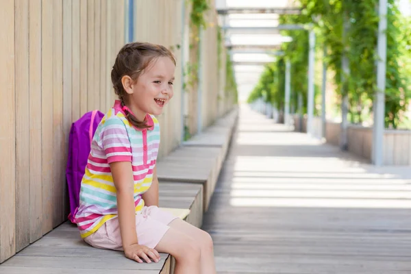 Okulun ilk günü. İlkokul gülümseme öğrencisi . Binanın yanında sırt çantası olan bir kız. Derslerin başlangıcı. Sonbaharın ilk günü. okula geri kavram