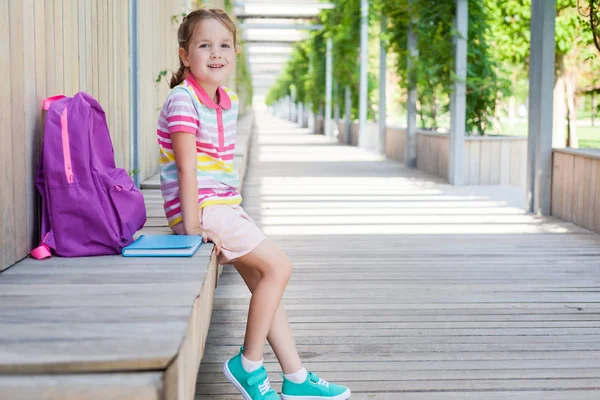 Okulun ilk günü. Elinde kitap olan ilkokul öğrencisi. . Binanın yanında sırt çantası olan bir kız. Derslerin başlangıcı. Sonbaharın ilk günü. okula geri kavram.