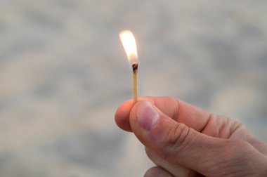 Maç sağ elinde yanan. Alev için yukarı işaret maçı. Yetişkin adam, kum arka plan. 