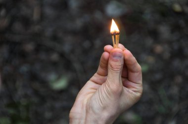 Maçlar sağ elinde yanan. Alev için yukarı işaret maçlar. Yetişkin adam, karanlık ormanın arka plan.