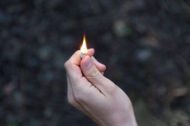 Maçlar sol elinde yanan. Alev için yukarı işaret maçlar. Yetişkin adam, karanlık ormanın arka plan.