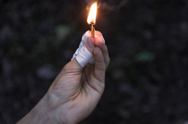 Maçlar sol elinde yanan. Alev için yukarı işaret maçlar. Yetişkin adam, karanlık ormanın arka plan.