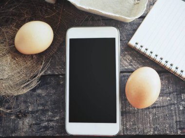 Akıllı telefon ve ahşap arka plan üzerinde yumurta