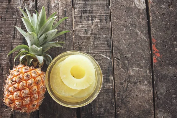 Canned pineapple on wood background