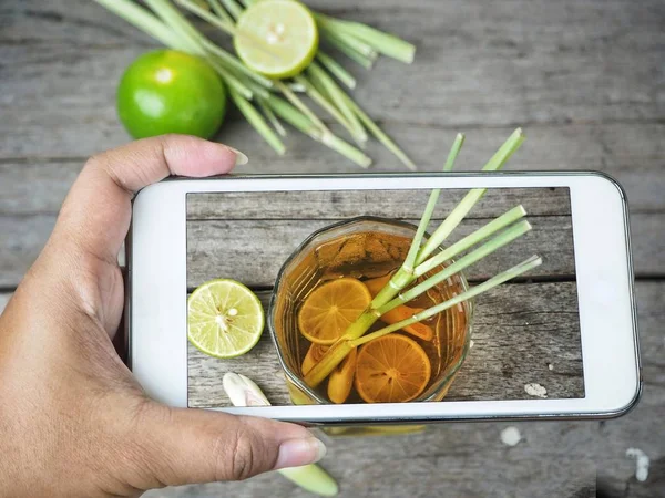 Taking a photo of lemon grass tea with smart phone on hand