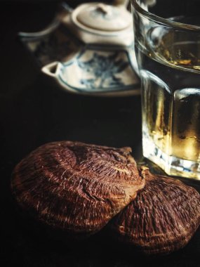 Ganoderma Lucidum - Ling Zhi Mushroom and tea pot on black background clipart