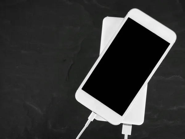 Power bank charger and smart phone on black background