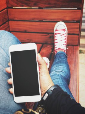 Yandan akıllı telefon kullanan kadın ve spor ayakkabı