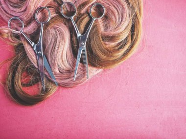 Saç kesme makası ve pembe bir arka plan üzerinde peruk