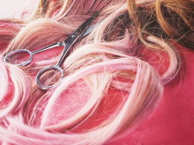 Saç kesme makası ve pembe bir arka plan üzerinde peruk