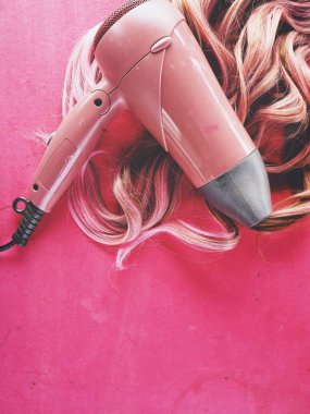 Saç kurutma makinesi ve pembe bir arka plan üzerinde peruk saç