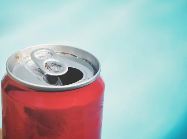 Cola can on hand swimming pool summer