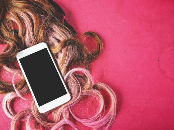 Akıllı telefon ve pembe bir arka plan üzerinde peruk