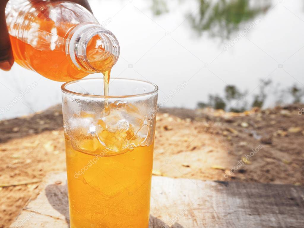Pouring orange soft drink with ice cubes