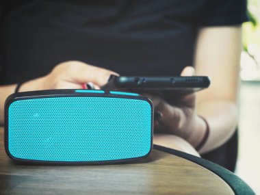 Akıllı telefon ve bluetooth hoparlör kullanan kadın