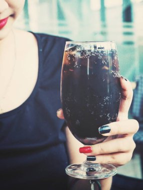 Kadın elinde kola içiyor.