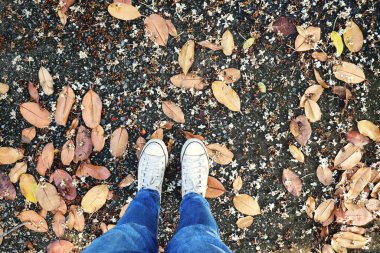 Kurumuş yaprakların üzerindeki beyaz spor ayakkabıların selfie 'si.