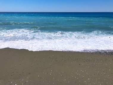 Kum, çakıl taşları ve deniz.