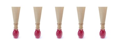 Geniş beyaz arka planda kırmızı iplikli fagot için çift kamış. Rüzgâr müzik aletleri için beş ağızlık. Hafif bir gölgeyle.