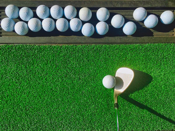 Group of golf ball on practice artificial grass mat with one ball ready with wedge iron under early morning sunlight