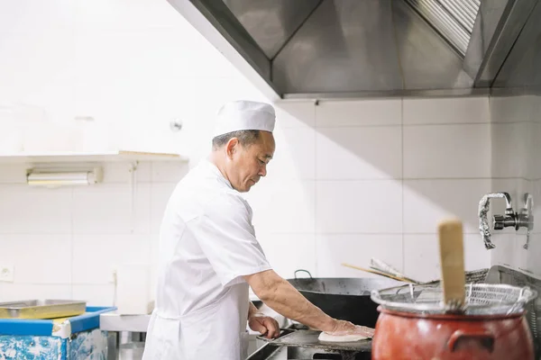 Asian chef works in the kitchen wok restaurant