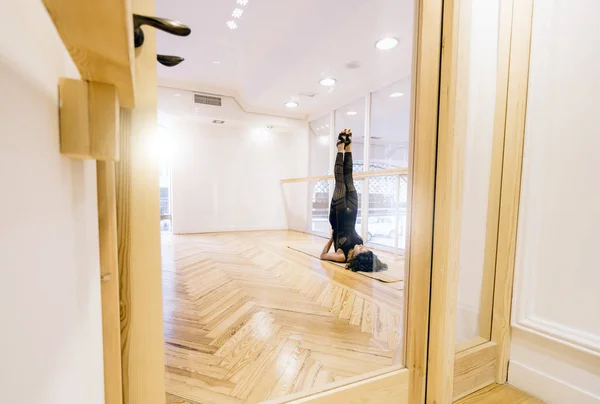 Latin woman performs yoga posture in nice room.