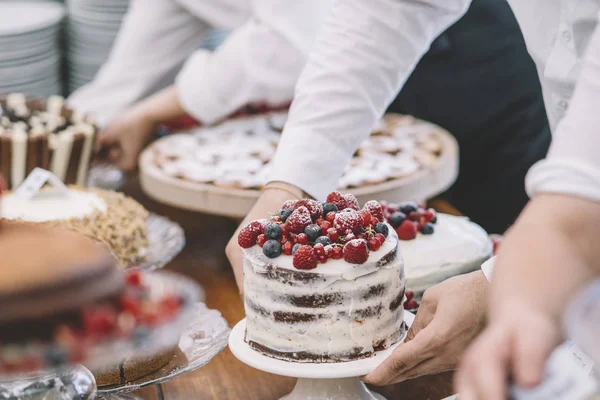 Display of sweet desserts at a celebration. People are served desserts on the plates.