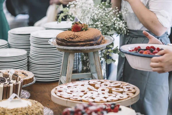 Display of sweet desserts at a celebration. People are served desserts on the plates.