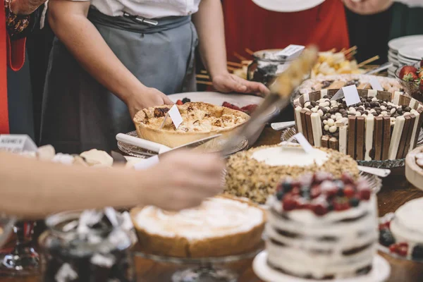 Display of sweet desserts at a celebration. People are served desserts on the plates.