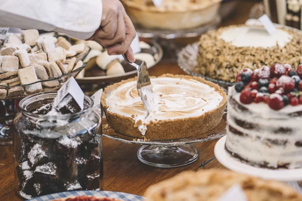 Display of sweet desserts at a celebration. People are served desserts on the plates.