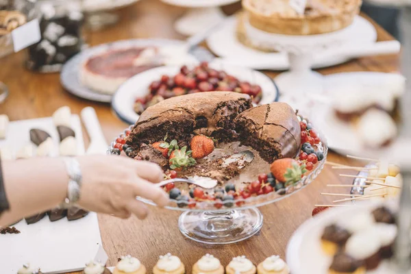 Display of sweet desserts at a celebration. People are served desserts on the plates.