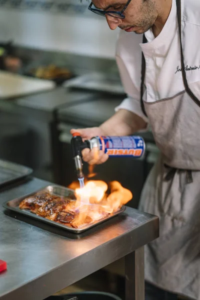 Chef cooking preparing food with fire torch.