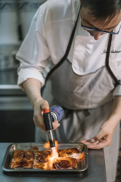 Chef cooking preparing food with fire torch.