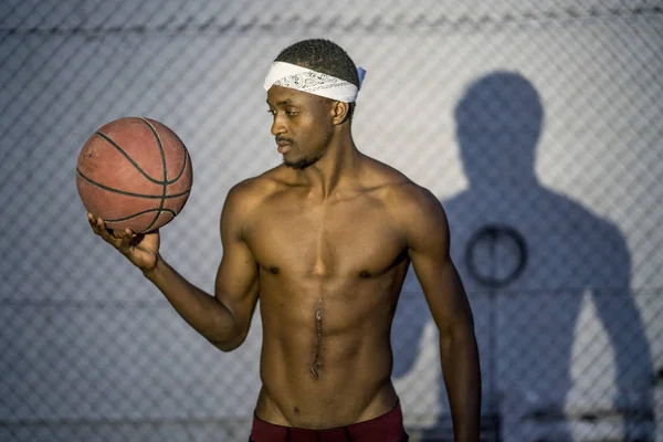 African man poses with basketball in the street