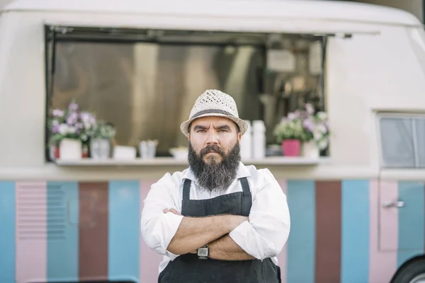 Big man with beard and hat serves food on food track