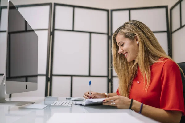 Pretty blonde woman works in office with computer.