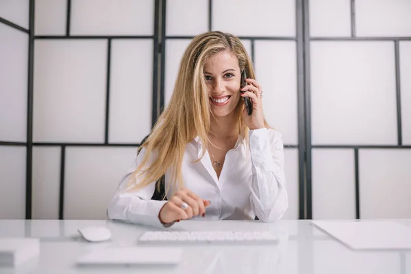 Pretty blonde woman works in office with computer.