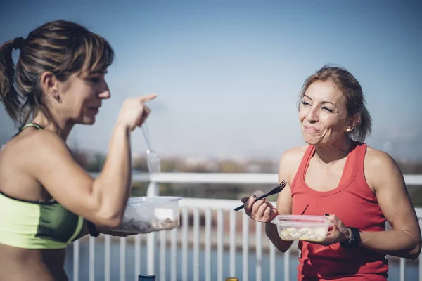 Two women eat outdoors after training