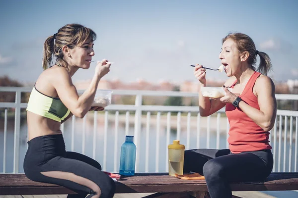 Two women eat outdoors after training