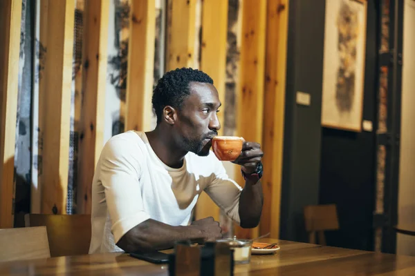 Handsome african man drinking a coffee in establishment.
