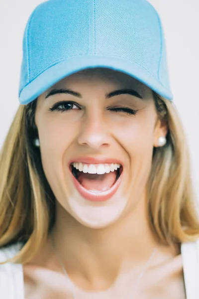 Pretty blond woman with blue baseball hat. Wink.
