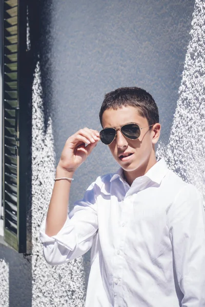 Young teenage boy with pilot sunglasses posing at camera.