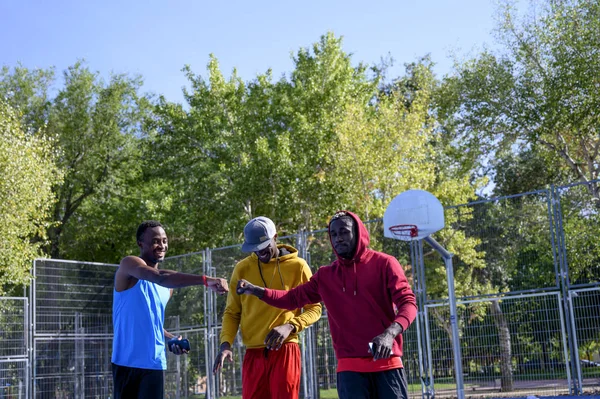 three African men greet each other on basketball court