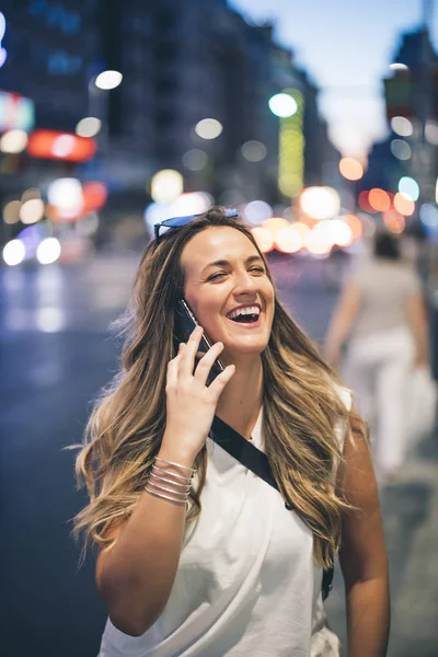 Pretty urban woman using phone in city of Madrid Spain at night