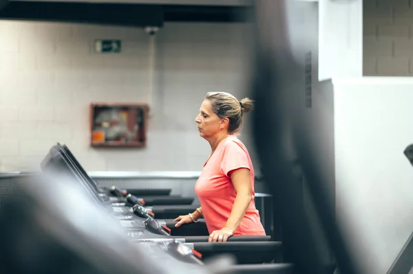 Retired senior woman doing sport in gym.