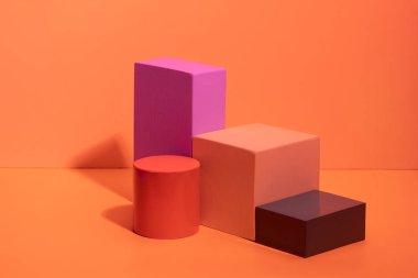 Turuncu arka planda farklı renklerde geometrik şekiller. Renkli kağıt üzerinde üç boyutlu katı rakamlar.