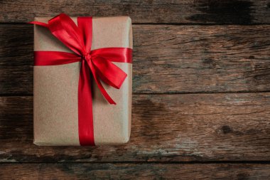 Brown hediye kutusu papyon kırmızı kurdele eski ahşap zemin üstü üzerinde görüntülemek neşeli Noel ve mutlu yeni yıl kavramı