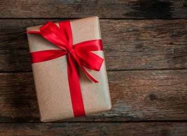 Brown hediye kutusu papyon kırmızı kurdele eski ahşap zemin üstü üzerinde görüntülemek neşeli Noel ve mutlu yeni yıl kavramı